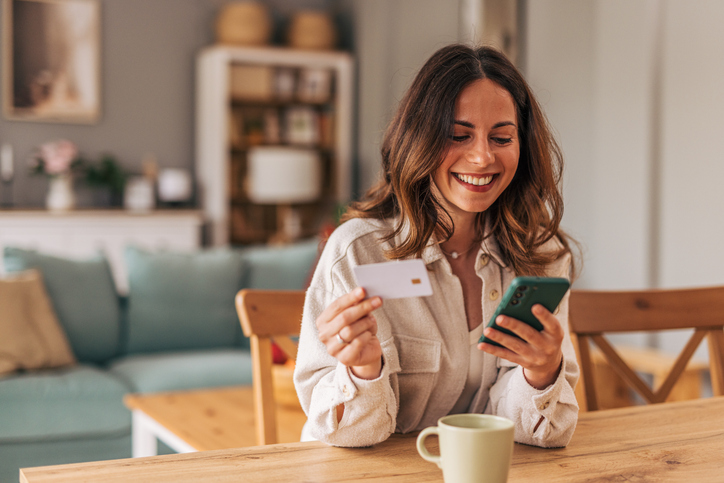 Woman smiling with a debit card and phone