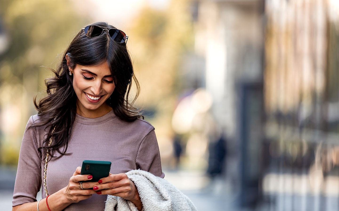 woman on sidewalk smiling at her phone