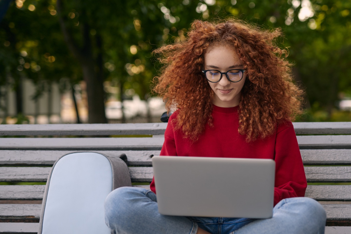 College student sitting on a bench with laptop