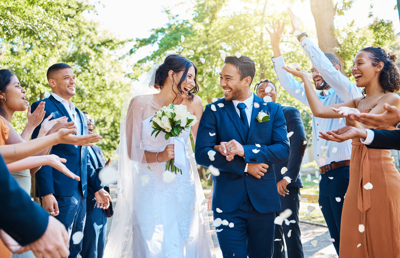 Wedding guests throwing rose petals confetti tradition over bride and groom on their special day