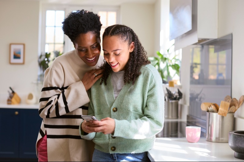 Mom and teen in kitchen looking at smartphone