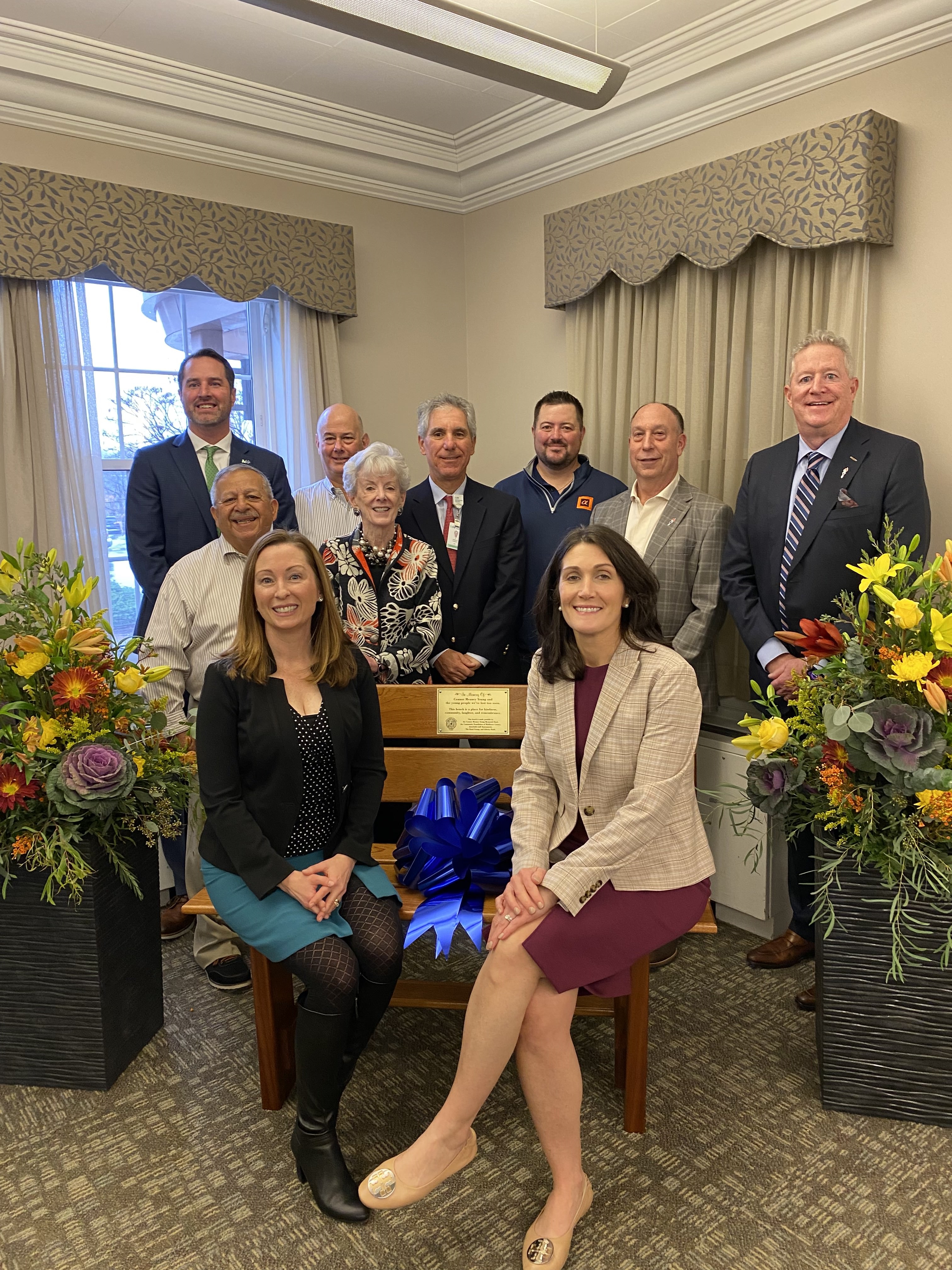 Group of people around and sitting on a bench that was donated