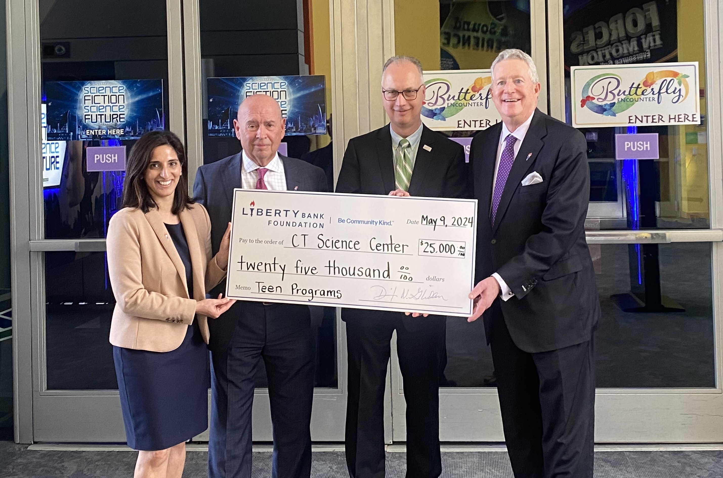 Four people holding a large grant check